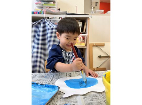 青い絵の具を筆で塗るこども①