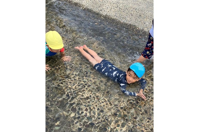 寝そべって水浴びをするこども
