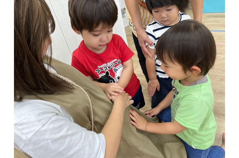 先生のおなかを触るこどもたち