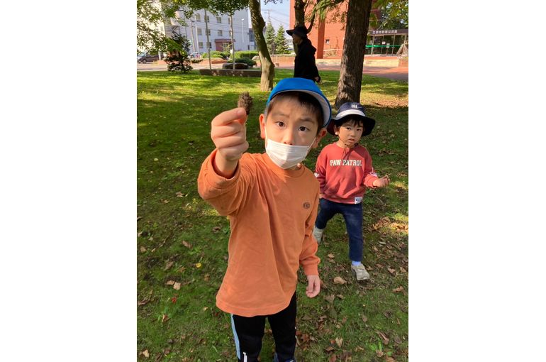 木の実をもってポーズする子ども