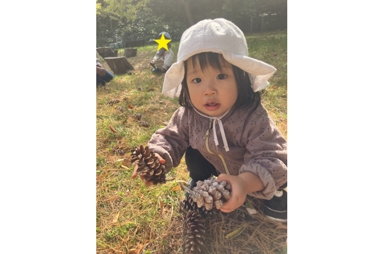 松ぼっくりを見せる子ども